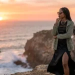 Stylish woman overlooking coastal cliffs at sunset
